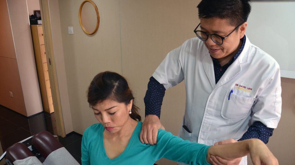 Chiropractor providing patient shoulder pain treatment
